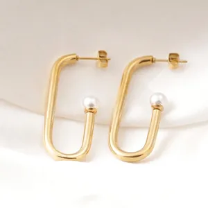 Chic gold U-shaped earrings featuring elegant white pearls on a soft silk background