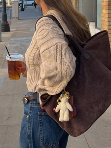 Foto street style di una borsa tote in camoscio marrone con orsetto di peluche in città