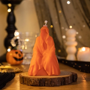 Detailed view of orange wax ghost candle on wood base with festive pumpkin lighting
