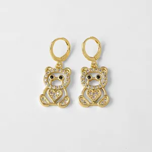 Pendientes de oso dorado con circonitas blancas y detalle de corazón en fondo gris
