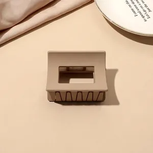 Detailed view of square matte brown claw clip on a neutral aesthetic background