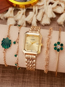 Close-up of a rectangular gold watch with green emerald flower bracelets on a display