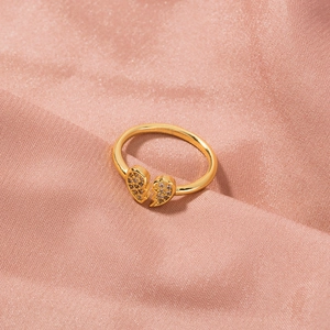 Macro shot of gold broken heart ring with cubic zirconia on pink satin fabric