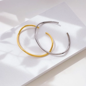 Detail shot of minimalist gold and silver open bracelets on elegant stone display