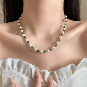 Close-up of green faceted beads and white pearls necklace worn on a model neck