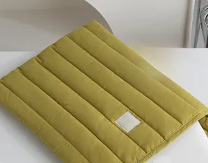 Close-up of quilted mustard green laptop sleeve with padded texture and square label
