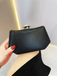 Detail van een zwarte glitter avondclutch in trapeziumvorm met zilveren strass sluiting