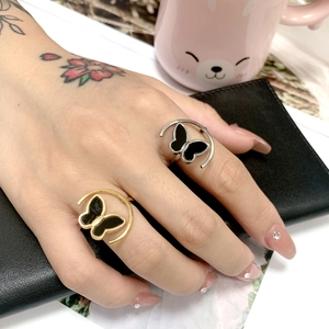 Close-up of gold and silver titanium steel rings with black butterfly designs on hand