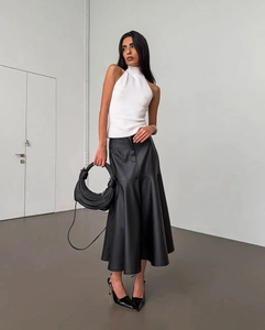 Détail d'une jupe mi-longue en cuir PU noir taille haute avec haut licou blanc élégant