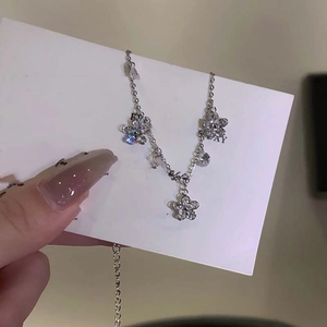 Detailed view of silver flower anklet with sparkling zircons held on a white display card