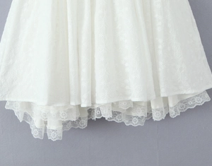 Vue détaillée de l'ourlet de robe blanche brodée avec des finitions en dentelle fine