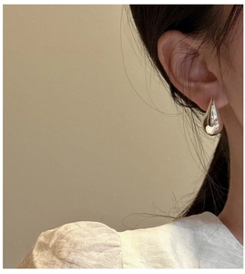 Detailed view of polished S925 sterling silver hollow teardrop earrings on a model