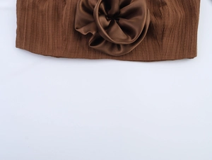 Detailed close-up of dark brown pleated fabric featuring a 3D satin floral decoration
