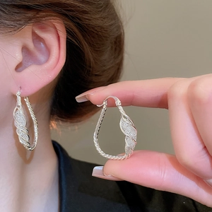 Detail of silver twisted rope hoop earrings with glitter inlay shown on model and held by hand