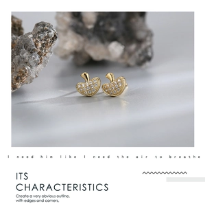 Detailed view of gold plated heart stud earrings with cubic zirconia on natural stone