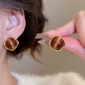 Detail of tiger eye stone earrings on model showing glossy brown gemstone and gold square base