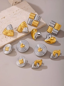 Close-up of geometric two-tone heart and square earrings with textured metal finish