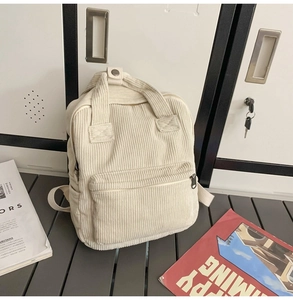 Detailansicht eines weißen Cord-Rucksacks mit Tragegriffen und vorderem Reißverschlussfach