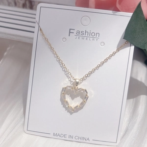 Macro detail of gold-plated heart pendant with zircon stones on silk background