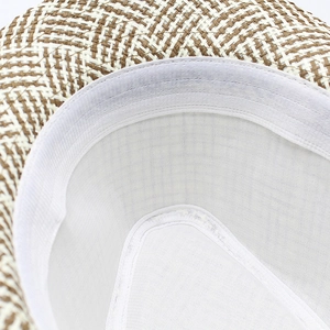 Detail view of the breathable lining and white sweatband inside a plaid straw fedora hat
