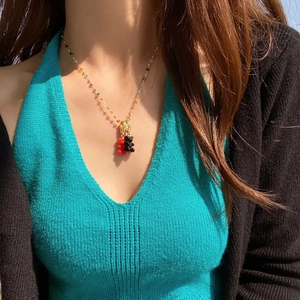 Close-up of beaded necklace featuring red and black resin gummy bear pendants on a model