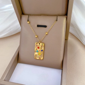 Minimalist square gold necklace with colorful gemstones displayed in a jewelry box
