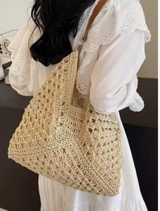 Dettaglio della borsa in paglia intrecciata con tracolla in pelle marrone sulla modella