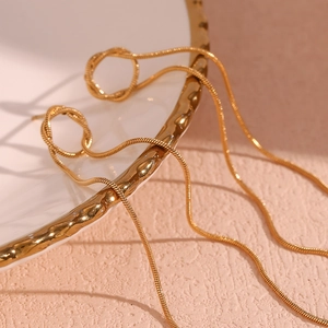 Elegant 18K gold plated stainless steel snake chain tassel earrings on a white ceramic tray