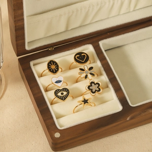Set of 7 gold-toned rings with colorful enamel sun, heart, and daisy motifs in a jewelry box
