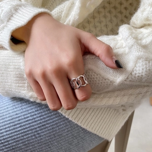 Detail of S925 sterling silver interlocking chain ring worn with a white knit sweater