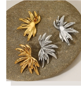 Polished 316 stainless steel wing earrings in gold and silver finish on a pebble
