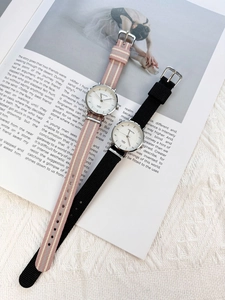 Close-up of minimalist quartz watches with striped and black canvas straps on magazine