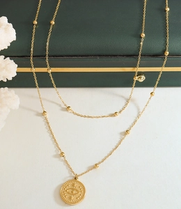 Close-up of 18k gold plated double layer necklace with evil eye coin pendant on jewelry box