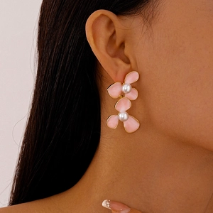 Pink floral pearl earrings with gold edges and layered petals worn by a model