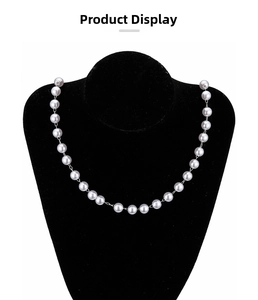 Detail of white faux pearl and brass bead chain on black velvet neck bust display