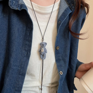 Détail d'un collier ours en denim avec perles et strass sur un cordon noir élégant
