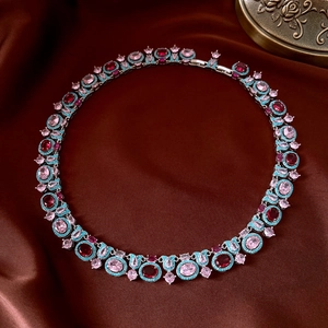Dettaglio collana vintage con pietre rosse, rosa e turchesi su sfondo in seta marrone