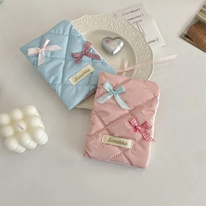 Quilted fabric passport covers in pink and blue featuring decorative ribbon bows