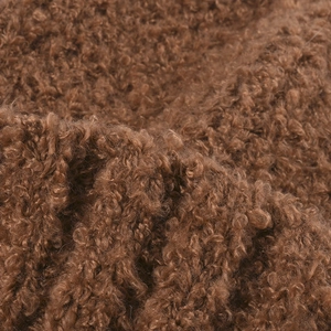 Detailopname van een dikke bruine bouclé gebreide stof voor warme wintermutsen en beanies.