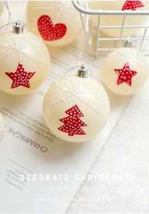 Detailed view of cream Christmas baubles with red heart and star patterns and silver hooks