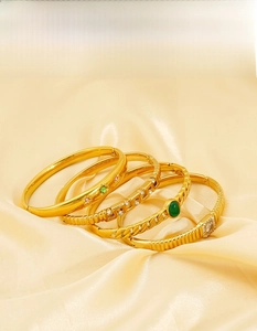 Detail of luxury gold plated stainless steel bracelets with zircon and green gemstones