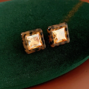 Macro detail of square amber gemstone earrings with tortoise shell resin frame