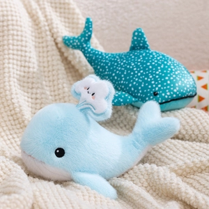 Cute blue whale and whale shark plush toys for kids on a soft knit blanket background