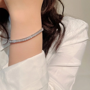 Close-up of a silver tennis bracelet with square-cut cubic zirconia on a model's wrist