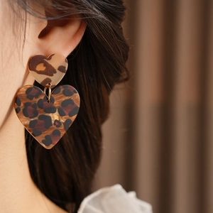 Detail view of heart-shaped leopard print earrings featuring a double-layered acrylic design