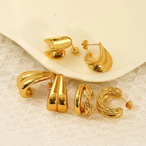 Three pairs of elegant gold-toned C-shaped hoop earrings on a ceramic jewelry tray