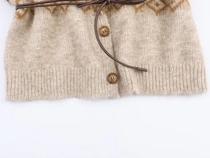 Dettaglio di cardigan in maglia con motivi a rombi, cintura sottile e bottoni in resina