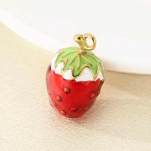 Macro detail of a red enamel strawberry pendant with gold loop for DIY jewelry making