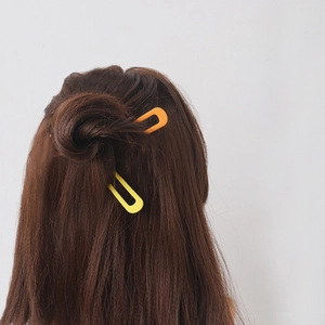 Minimalist U-shaped hair pins in bright yellow and orange for elegant bun styling