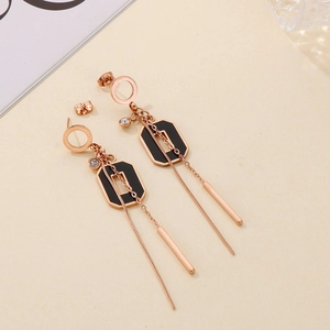 Gros plan de boucles d'oreilles à pampilles en or rose avec émail noir et zircons